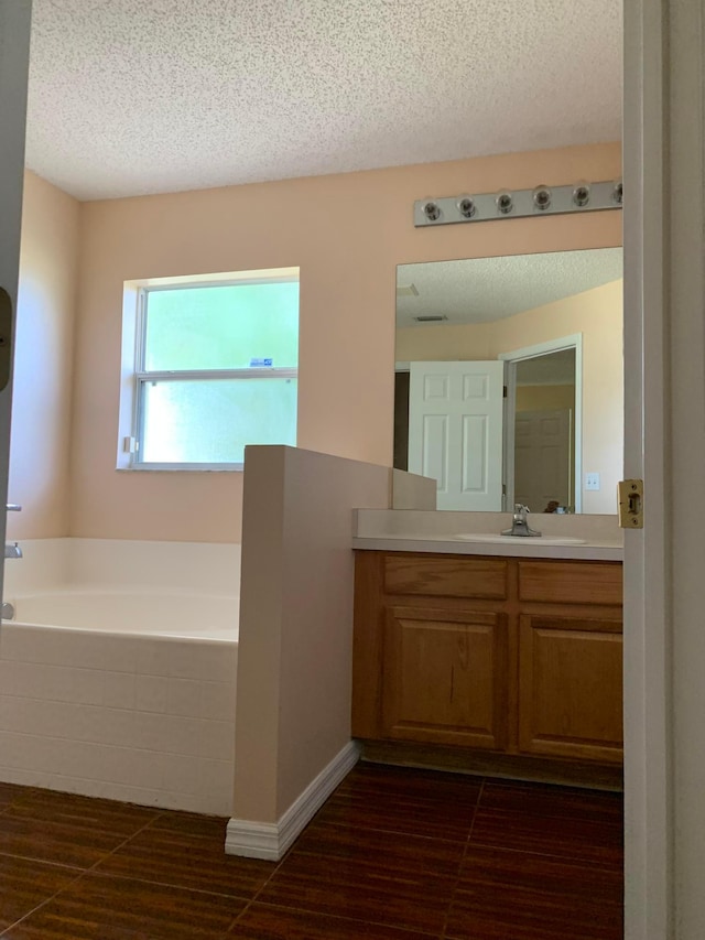 bathroom featuring tile floors, a textured ceiling, vanity, and a bath to relax in