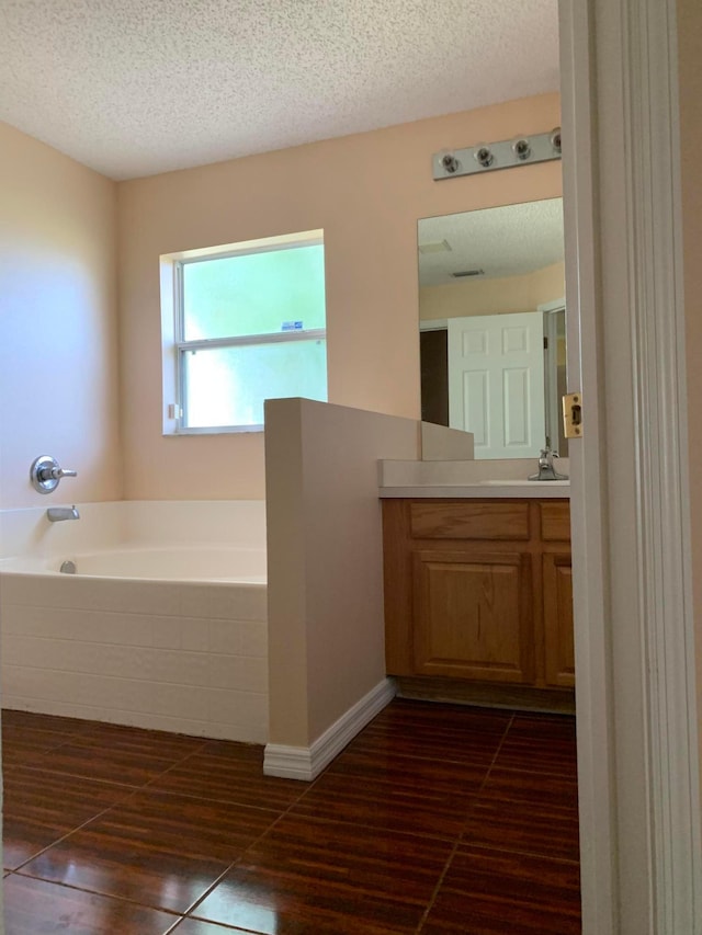 bathroom with a textured ceiling, a washtub, vanity, and tile flooring