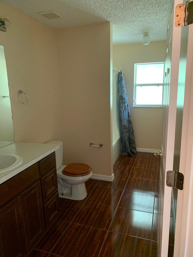 full bathroom featuring vanity, tile floors, shower / bathtub combination with curtain, a textured ceiling, and toilet