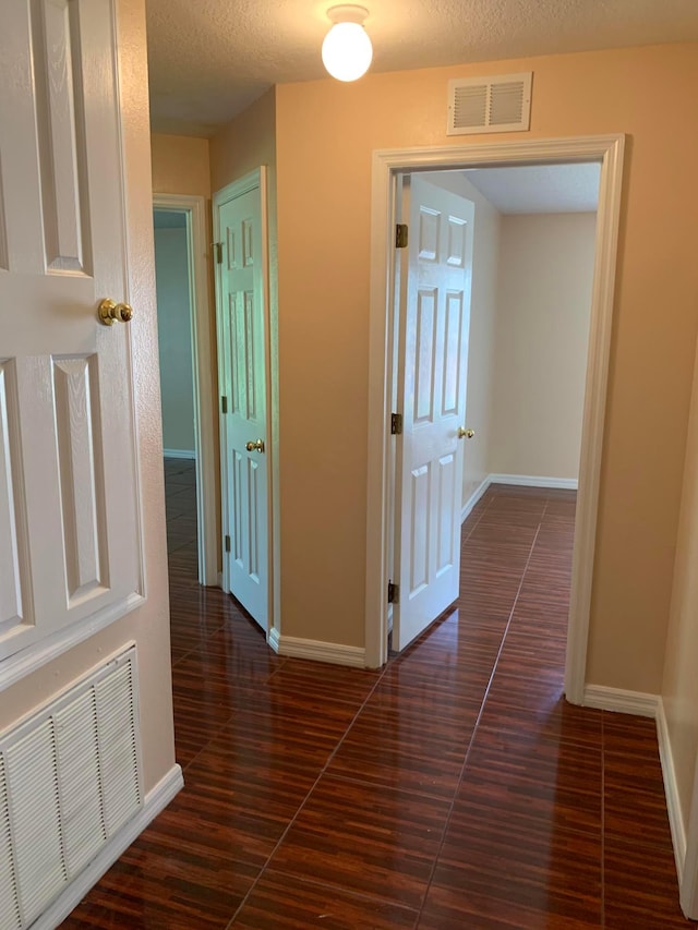 corridor with a textured ceiling and dark hardwood / wood-style floors