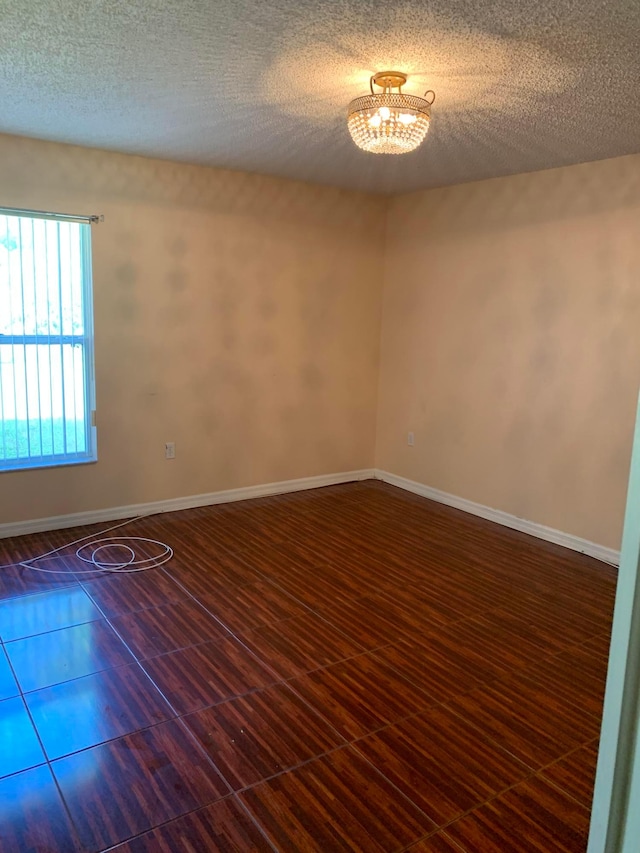 unfurnished room featuring a textured ceiling and a notable chandelier