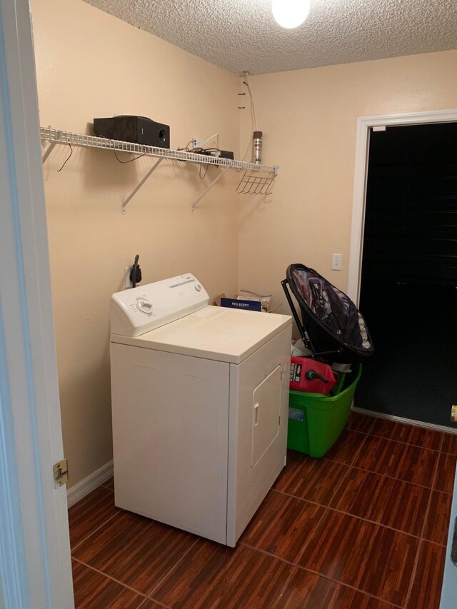 laundry area featuring dark tile floors, a textured ceiling, and washer / dryer