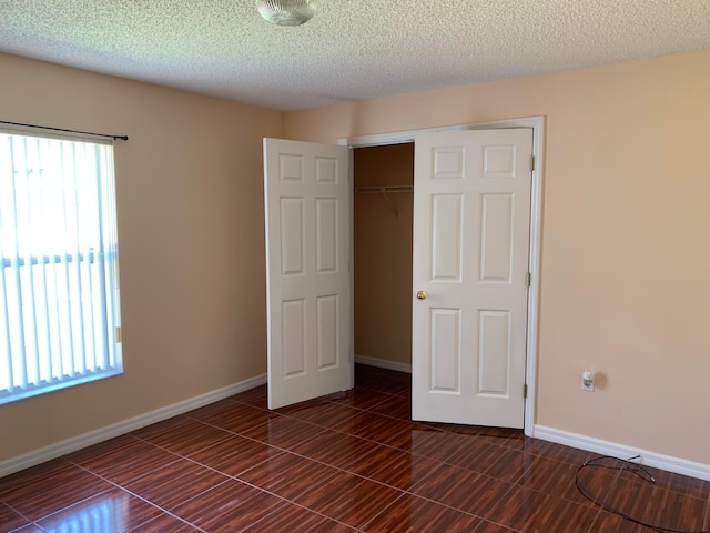 unfurnished bedroom featuring a closet, dark tile floors, and a textured ceiling