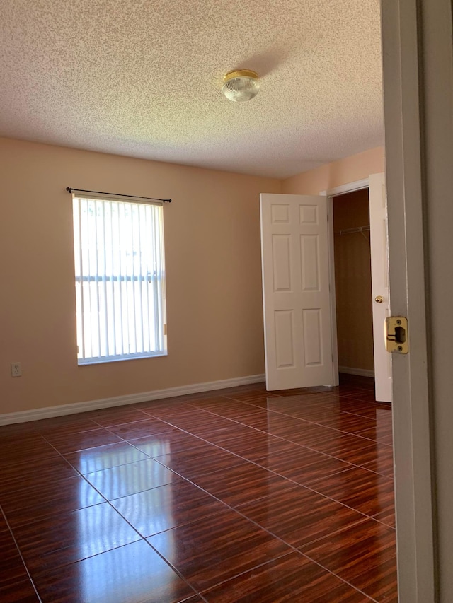 spare room featuring a textured ceiling and dark tile flooring