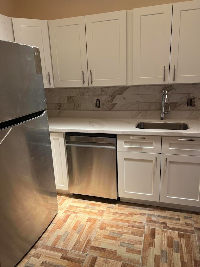 kitchen featuring sink, decorative backsplash, white cabinets, and stainless steel appliances