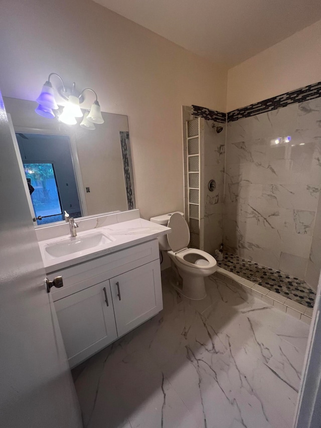 bathroom featuring tile patterned floors, vanity, a tile shower, and toilet