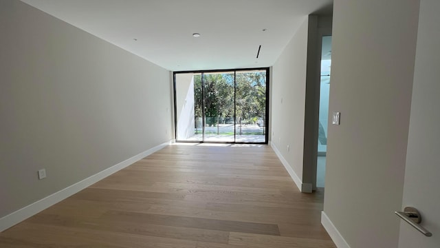 unfurnished room featuring light hardwood / wood-style floors and a wall of windows