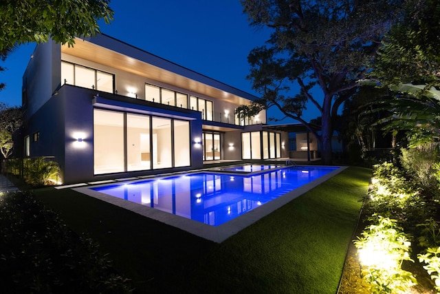 pool at twilight featuring a lawn and a patio area