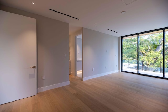 empty room with light hardwood / wood-style floors and a wall of windows