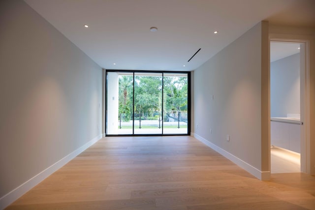 spare room with floor to ceiling windows and light hardwood / wood-style flooring