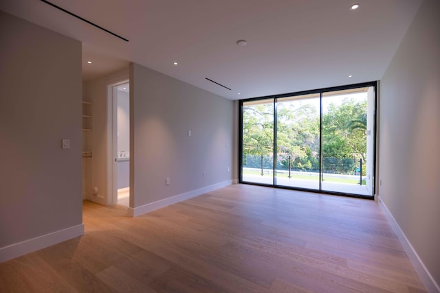 spare room featuring a wall of windows and light hardwood / wood-style flooring