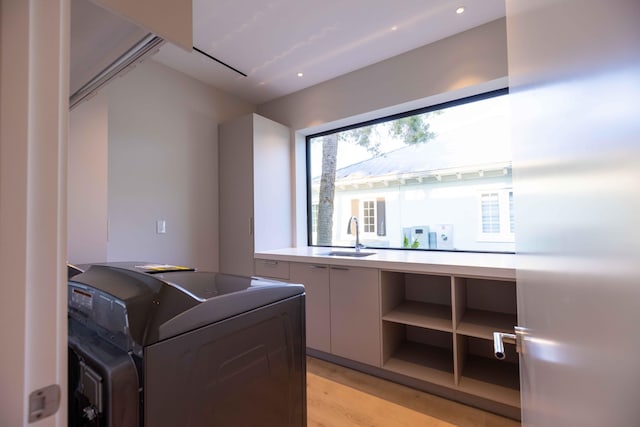 laundry room with light hardwood / wood-style floors and sink