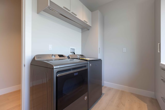 clothes washing area featuring washer and dryer, washer hookup, cabinets, and light wood-type flooring