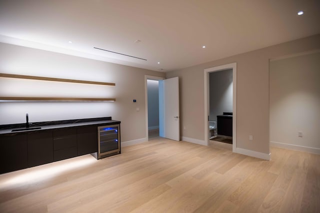 interior space with ensuite bath, sink, beverage cooler, and light wood-type flooring