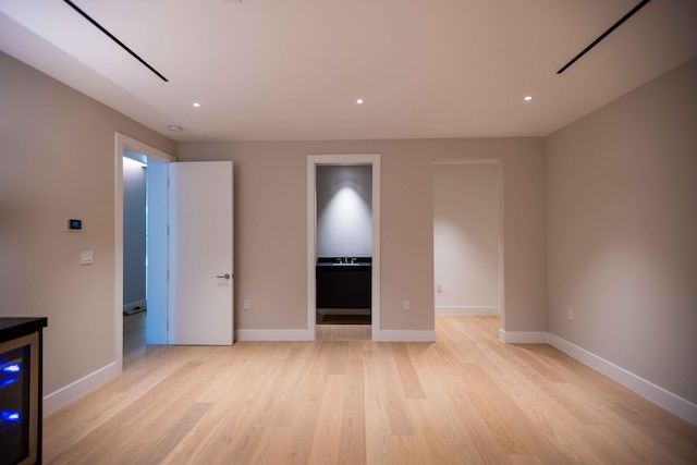 unfurnished room featuring wine cooler and light hardwood / wood-style flooring