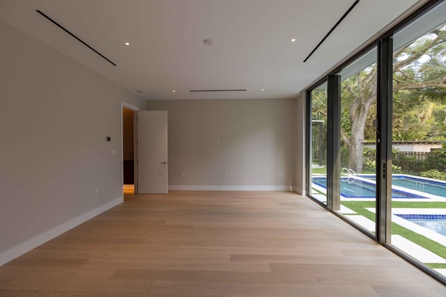 unfurnished room featuring a wall of windows and light wood-type flooring