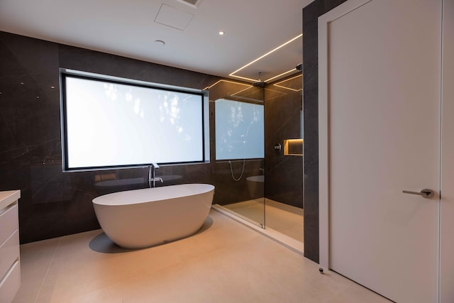 bathroom with vanity, tile flooring, plus walk in shower, and tile walls