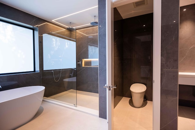 bathroom featuring independent shower and bath, tile walls, and tile floors