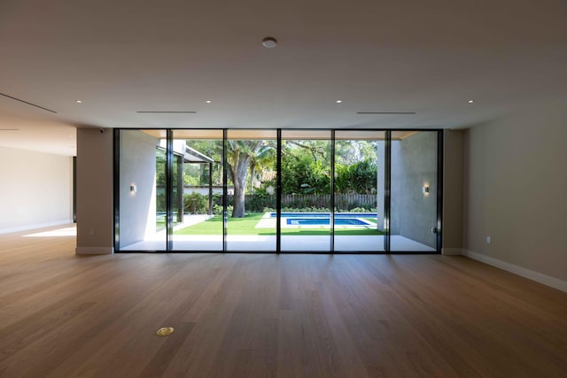 unfurnished room featuring expansive windows and hardwood / wood-style flooring