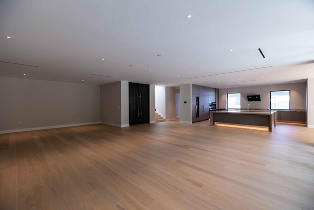 unfurnished living room with light wood-type flooring and sink