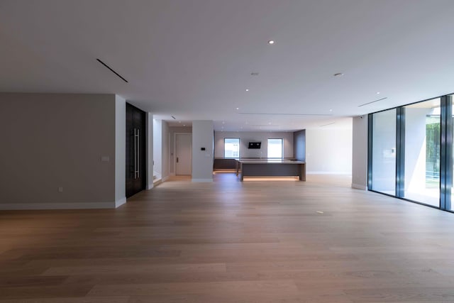 unfurnished living room with floor to ceiling windows and light wood-type flooring