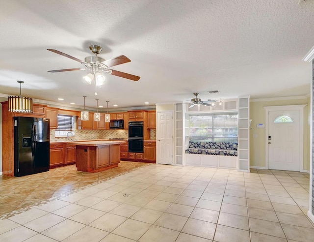 kitchen featuring a center island, sink, decorative light fixtures, light tile patterned flooring, and black appliances