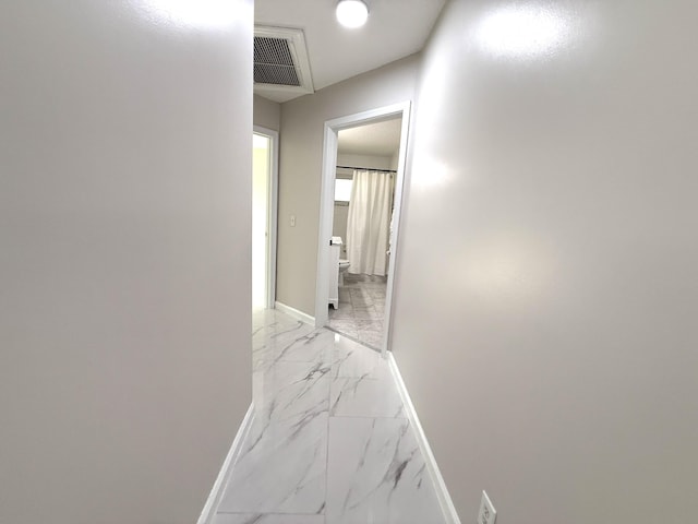 hallway with visible vents, marble finish floor, and baseboards