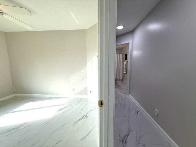 hallway with baseboards and marble finish floor