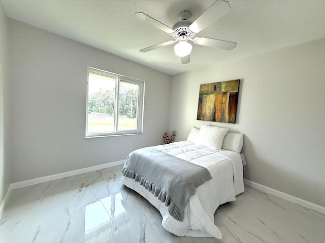 bedroom featuring marble finish floor, a textured ceiling, baseboards, and a ceiling fan