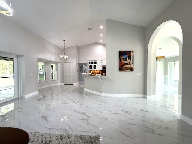 unfurnished living room featuring visible vents, high vaulted ceiling, marble finish floor, an inviting chandelier, and a healthy amount of sunlight