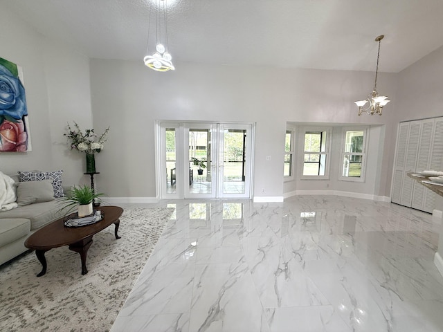 living area with a notable chandelier, marble finish floor, a high ceiling, and baseboards