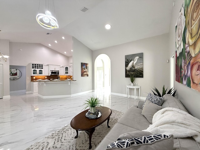 living area with visible vents, lofted ceiling, marble finish floor, arched walkways, and baseboards