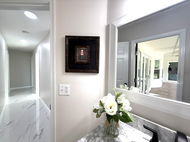 corridor with marble finish floor and baseboards