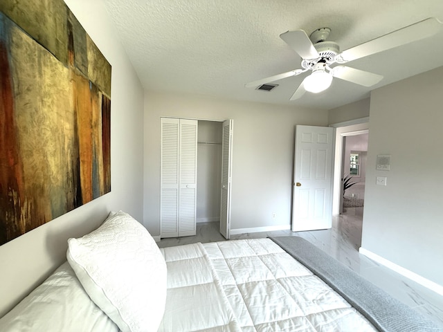 bedroom with marble finish floor, a textured ceiling, a closet, baseboards, and ceiling fan