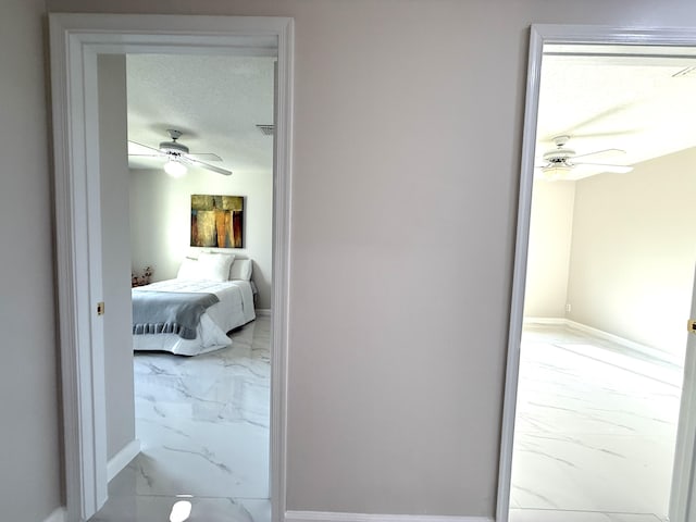 hall featuring baseboards, marble finish floor, and a textured ceiling