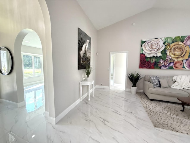 interior space with arched walkways, marble finish floor, high vaulted ceiling, and baseboards