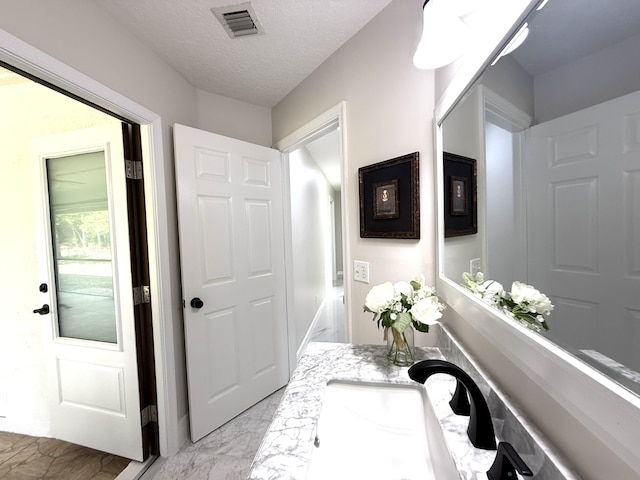 bathroom with vanity, visible vents, marble finish floor, and a textured ceiling