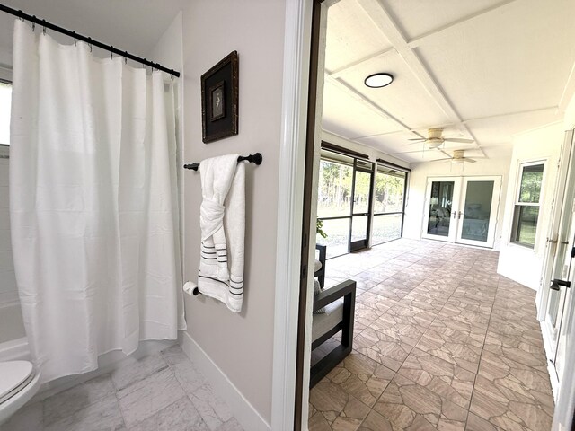 full bath with toilet, marble finish floor, shower / tub combo with curtain, baseboards, and ceiling fan