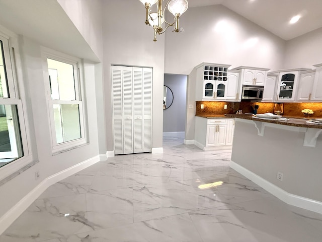 kitchen with stainless steel microwave, a kitchen breakfast bar, glass insert cabinets, and marble finish floor