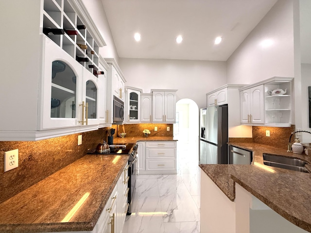 kitchen featuring marble finish floor, a sink, open shelves, dark stone counters, and appliances with stainless steel finishes