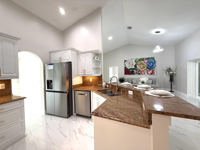 kitchen with dark stone countertops, a peninsula, a sink, appliances with stainless steel finishes, and marble finish floor