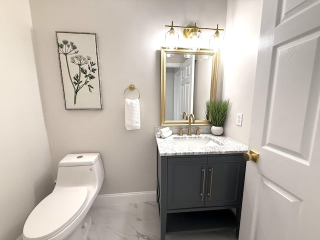 half bath featuring marble finish floor, toilet, vanity, and baseboards