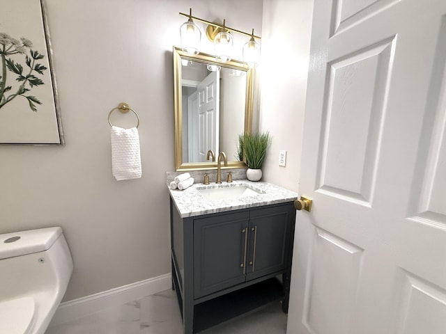 bathroom featuring baseboards, toilet, marble finish floor, and vanity