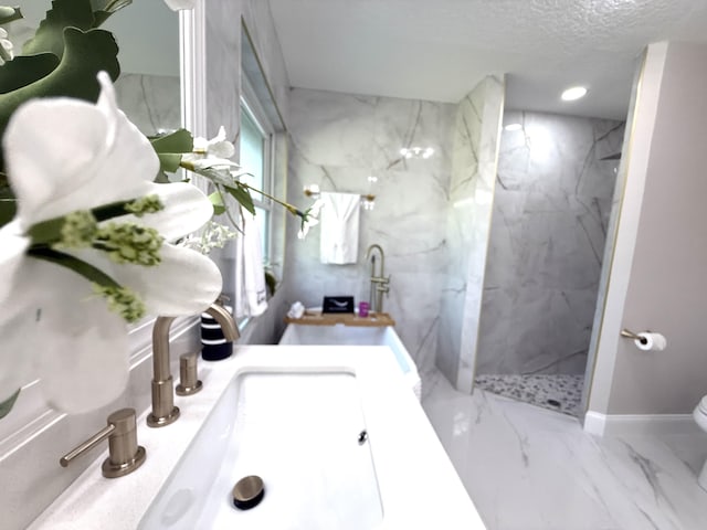 bathroom featuring toilet, marble finish floor, a textured ceiling, a marble finish shower, and vanity