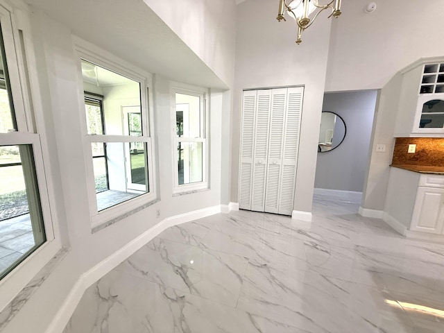 interior space with multiple windows, baseboards, marble finish floor, and a closet