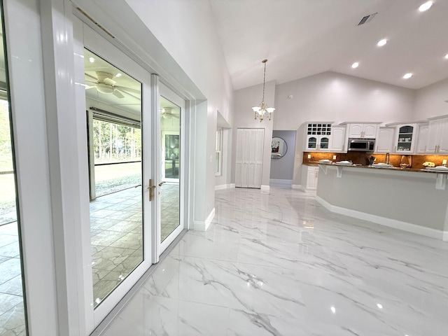 kitchen featuring stainless steel microwave, glass insert cabinets, baseboards, white cabinets, and marble finish floor