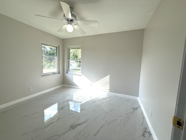 empty room featuring a textured ceiling, baseboards, marble finish floor, and ceiling fan