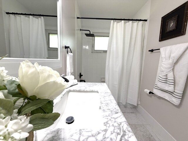 bathroom with shower / bath combination with curtain, marble finish floor, vanity, and baseboards