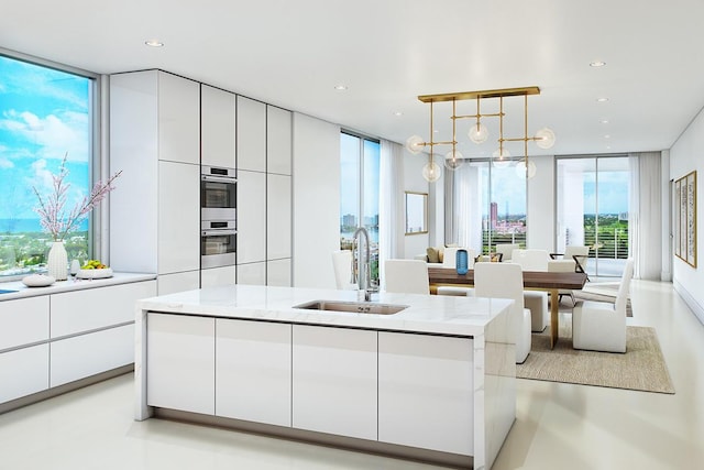 kitchen with white cabinetry, hanging light fixtures, light stone counters, and floor to ceiling windows