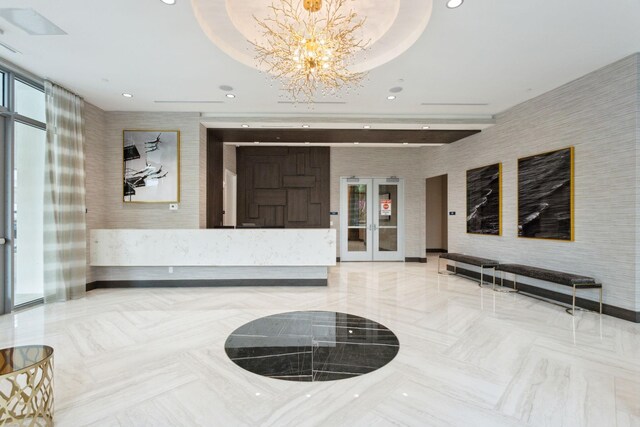 tiled living room with a notable chandelier, a raised ceiling, a wealth of natural light, and tile walls